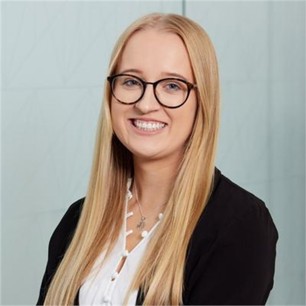 Darcey Sutcliffe in a white top and black cardigan, in front of a pale background